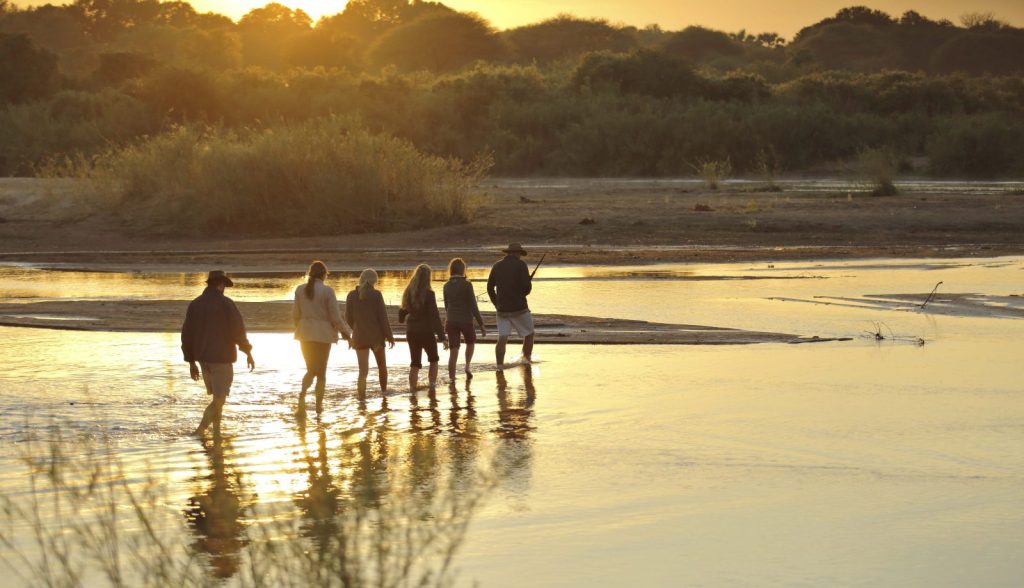 6 people walking through a flooded plain at sunset