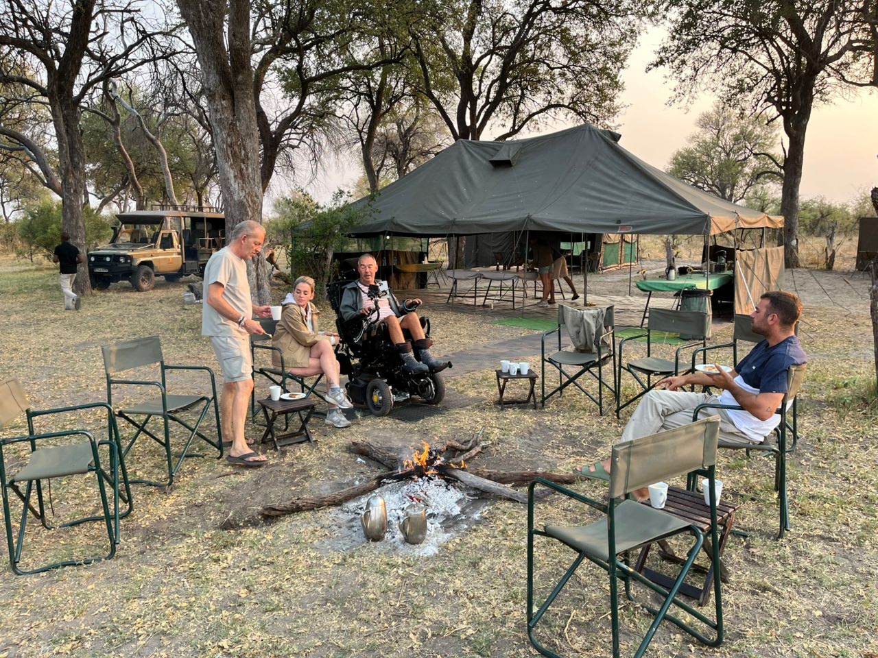 Wheelchair user sits around the fire in mobile camp in the Okavango Delta