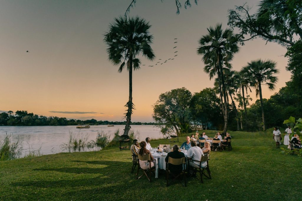 Guests eating dinner by the Zambezi River at the Palm Hotel